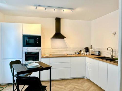 une cuisine avec des armoires blanches, une table et une cuisinière dans l'établissement Chez Louis - Le Rémois Du Centre, à Reims