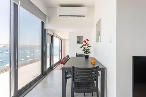 - une salle à manger avec une table, des chaises et de grandes fenêtres dans l'établissement SkyView Penthouse, Mell_4, à Mellieħa