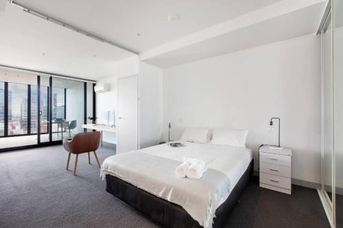 a bedroom with a bed and a desk and a chair at Flinders Street Simplicity Overlooking the Yarra in Melbourne