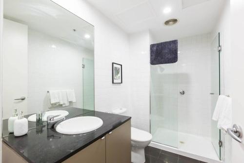 ein weißes Bad mit einem Waschbecken und einer Dusche in der Unterkunft A Coveted Collins Street Pad with Parking in Melbourne