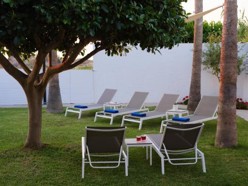 a group of chairs and tables under a tree at Sea La Vie in Adelianos Kampos