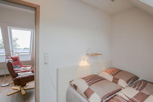 ein Schlafzimmer mit einem Bett, einem Stuhl und einem Spiegel in der Unterkunft Nordsee & Wald in Husum