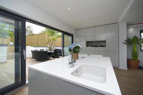 a white kitchen with a sink and a living room at Brighton Seaside Retreat in Falmer