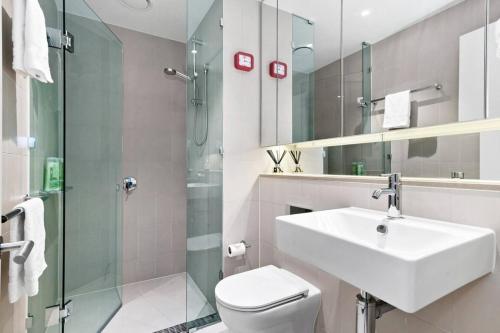 a bathroom with a sink and a toilet and a shower at Resort-style Docklands Riverview Stay with Parking in Melbourne