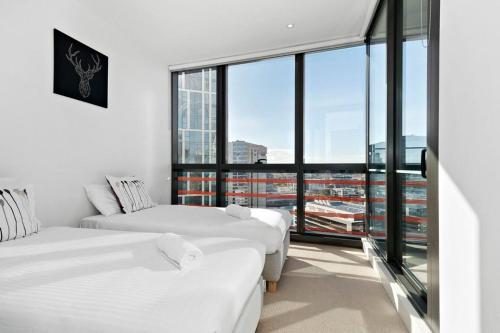 two beds in a room with a large window at Resort-style Docklands Riverview Stay with Parking in Melbourne