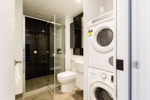 a bathroom with a toilet and a washer and dryer at 'Santeri' A Simple Stay with Modern Facilities in Melbourne