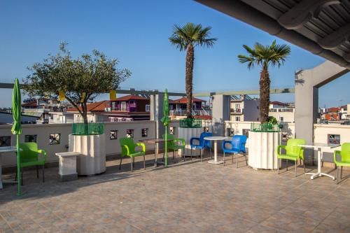 d'une terrasse avec des tables, des chaises et des palmiers. dans l'établissement Hotel Europe, à Paralia Katerinis