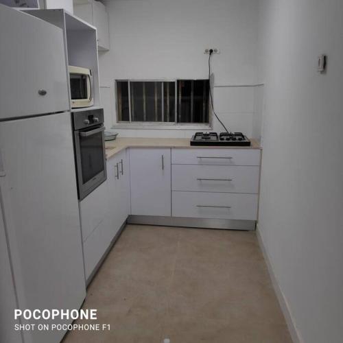 a kitchen with white cabinets and a white refrigerator at דירה פרטית מהממת מוארת. ממוזגת מרוהטת ומקסימה in Beer Sheva