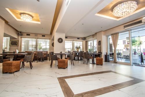 a lobby with tables and chairs and windows at Hotel Europe in Paralia Katerinis