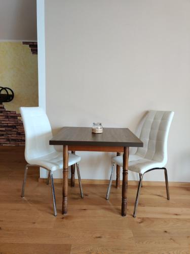 a wooden table with two white chairs around it at Festl Apartments in Forstern