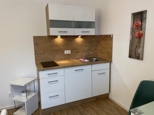una cocina con armarios blancos y fregadero en Festl Apartments - Nähe Messe München, Therme Erding, en Forstern