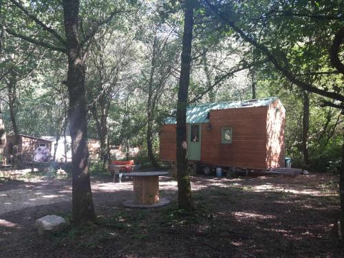 eine Hütte im Wald mit einer Bank und Bäumen in der Unterkunft Tiny house in Miélan