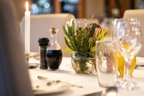 a table with a candle and a vase of flowers on it at De Zeekoe Guest Farm in Oudtshoorn