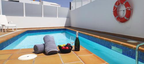 a swimming pool with a bottle of wine and a glass at Villa Tingafa in Yaiza