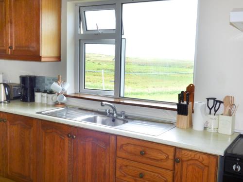 eine Küche mit einem Waschbecken und einem Fenster in der Unterkunft Ocean View in Louisburgh