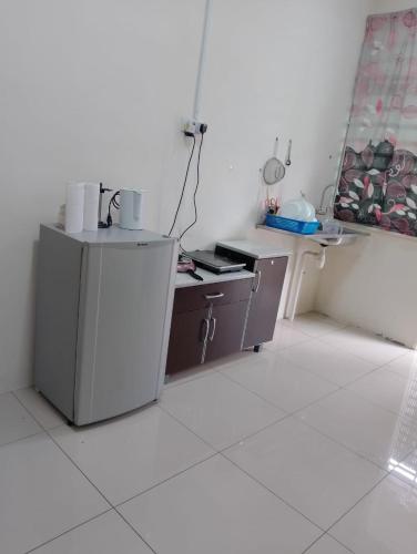 a small kitchen with a refrigerator and a table at RNK BoutiQue HOTEL in Jitra
