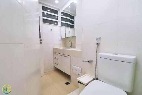 Baño blanco con aseo y lavamanos en Moderno 2 quartos p/ 6 pessoas a 50m da praia, en Río de Janeiro