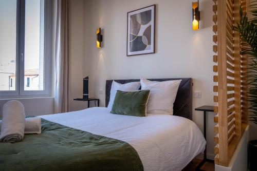 a bedroom with a bed with white sheets and green pillows at Le Napoléon in Vichy