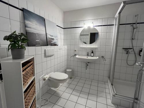 a white bathroom with a toilet and a sink at Gulfhof im historischen Kern in Krummhörn