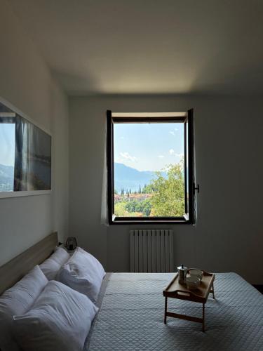 een slaapkamer met een bed met een tafel en een raam bij Casa NiMa Lake Apartment in Perledo