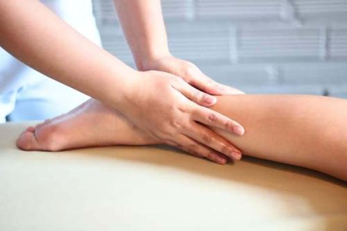 a woman is wrapping her legs on a table at GOLDEN LOTUS SPA & HOMESTAY in Ấp Thiện Phước