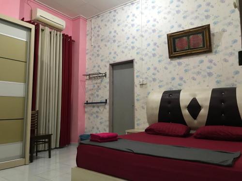 um quarto com uma cama com almofadas vermelhas em SAHMURA HOMESTAY 1 at GONG BADAK em Kuala Terengganu