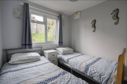 2 Einzelbetten in einem Zimmer mit Fenster in der Unterkunft Sealark in Bridport