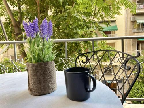 una tazza di caffè nera e un vaso con fiori viola sul tavolo di Raise Kolonaki Elegant Citybreak ad Atene