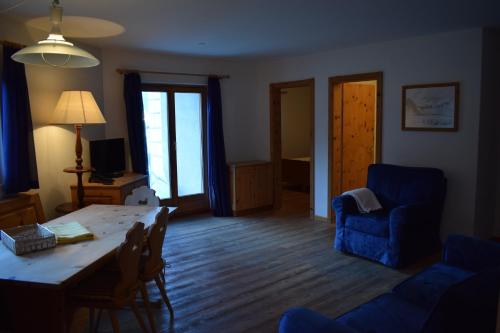 a living room with a table and a blue couch at Residence Miragolf in Madulain