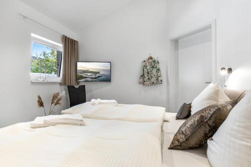 two white beds in a white bedroom with a window at Wellness- Doppelhaushälfte "Meer" in Fehmarn