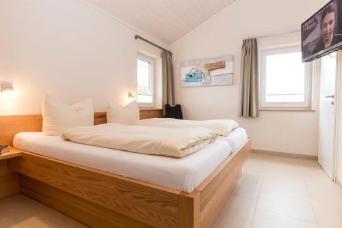 a bedroom with a large bed with white sheets at Wellnesshaus "Wind" in Fehmarn