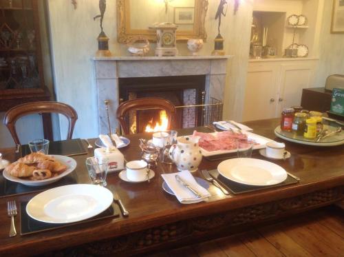 Newton Cottage في بورثكول: طاولة مع أطباق من الطعام ومدفأة