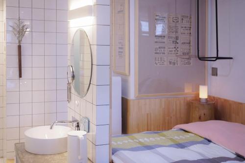 a bathroom with a sink and a bed and a mirror at TGS Studio Hotel in Guangzhou