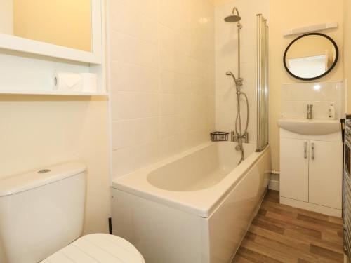 a bathroom with a tub and a toilet and a sink at 123 On The Sea in Weymouth