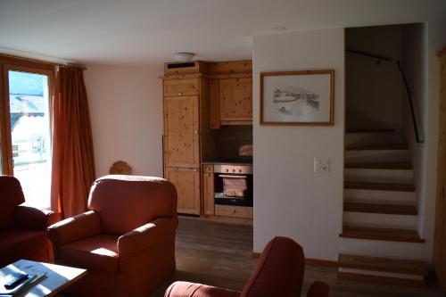 a living room with a couch and a stair case at Residence Miragolf in Madulain