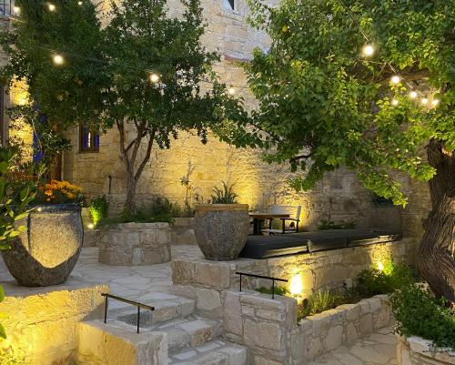 a patio with two benches and trees and lights at Apokryfo Traditional Guesthouse in Lofou