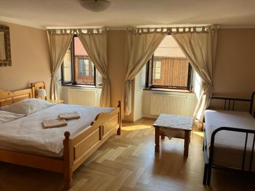 a bedroom with a large bed and two windows at Pension U Mrázků in Český Krumlov