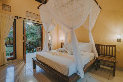 1 dormitorio con cama con dosel y cortinas blancas en Dija, en Pemuteran
