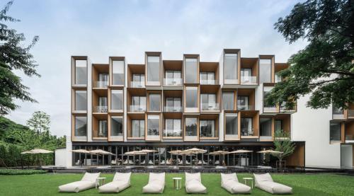 an exterior view of a building with chairs and umbrellas at Riva Vista Riverfront Resort Chiang Rai in Chiang Rai