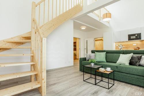 a living room with a green couch and stairs at KORZO LIPNO C in Lipno nad Vltavou