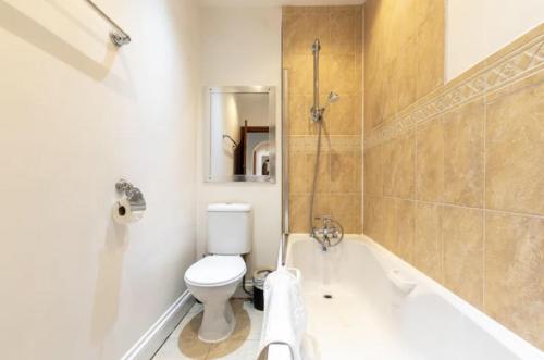 a bathroom with a toilet and a tub and a sink at Metropolitan - 203 Millbrook Road East in Southampton