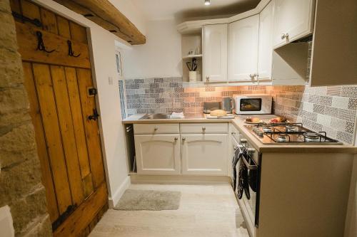 eine Küche mit weißen Schränken und einem Herd mit Backofen in der Unterkunft Swan House in Huddersfield