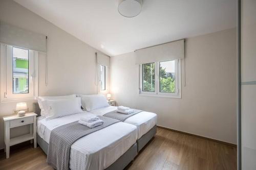 a white bedroom with a bed and two windows at YoZa Villa in Kokkíni Khánion