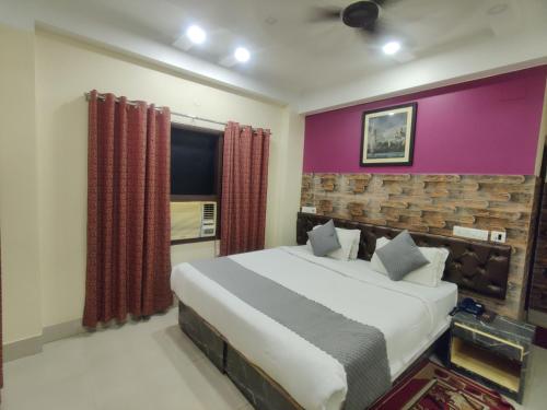 a bedroom with a large bed and a purple wall at Hotel Swastik Regency in Siliguri