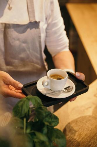 a person holding a tray with a cup of coffee on it at Schönherr Haus in Neustift im Stubaital