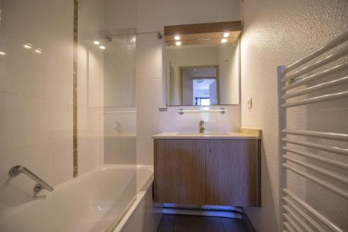 a bathroom with a sink and a tub and a mirror at VVF Résidence Anglet in Anglet