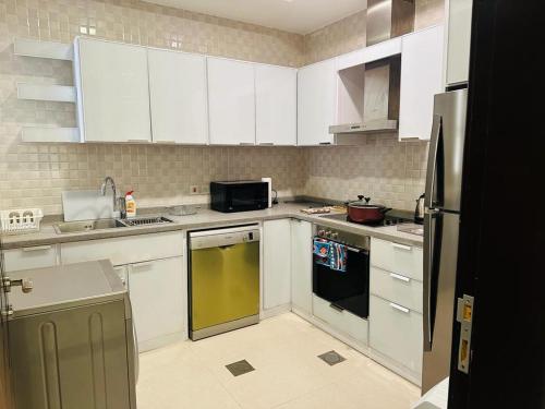 eine Küche mit weißen Schränken und einem gelben Geschirrspüler in der Unterkunft كرم النخلة للشقق المخدومة in Riad