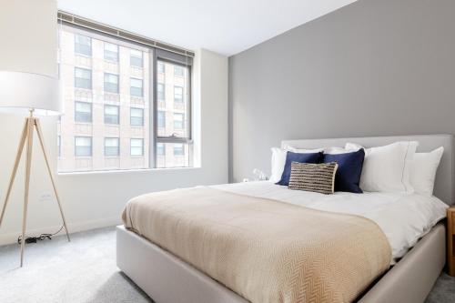 a white bedroom with a large bed and a window at Loop 1BR w Pool Gym nr Financial District CHI-268 in Chicago