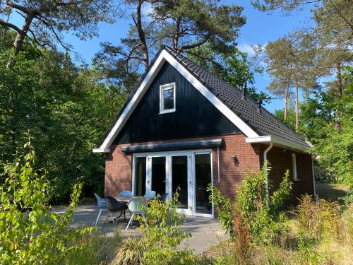 een klein rood bakstenen huis met een zwart dak bij Luxe Vakantiehuis Vosje op de Veluwe Nunspeet in Nunspeet