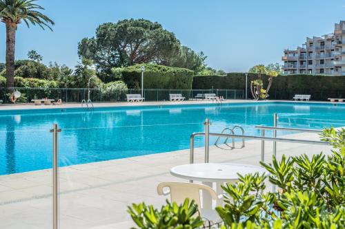 - une piscine avec une table en face d'un bâtiment dans l'établissement My Resid Appart Cannes marina vue mer, à Mandelieu-la-Napoule